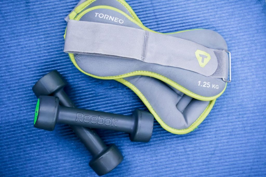 Dumbbells and ankle weights arranged on a blue exercise mat