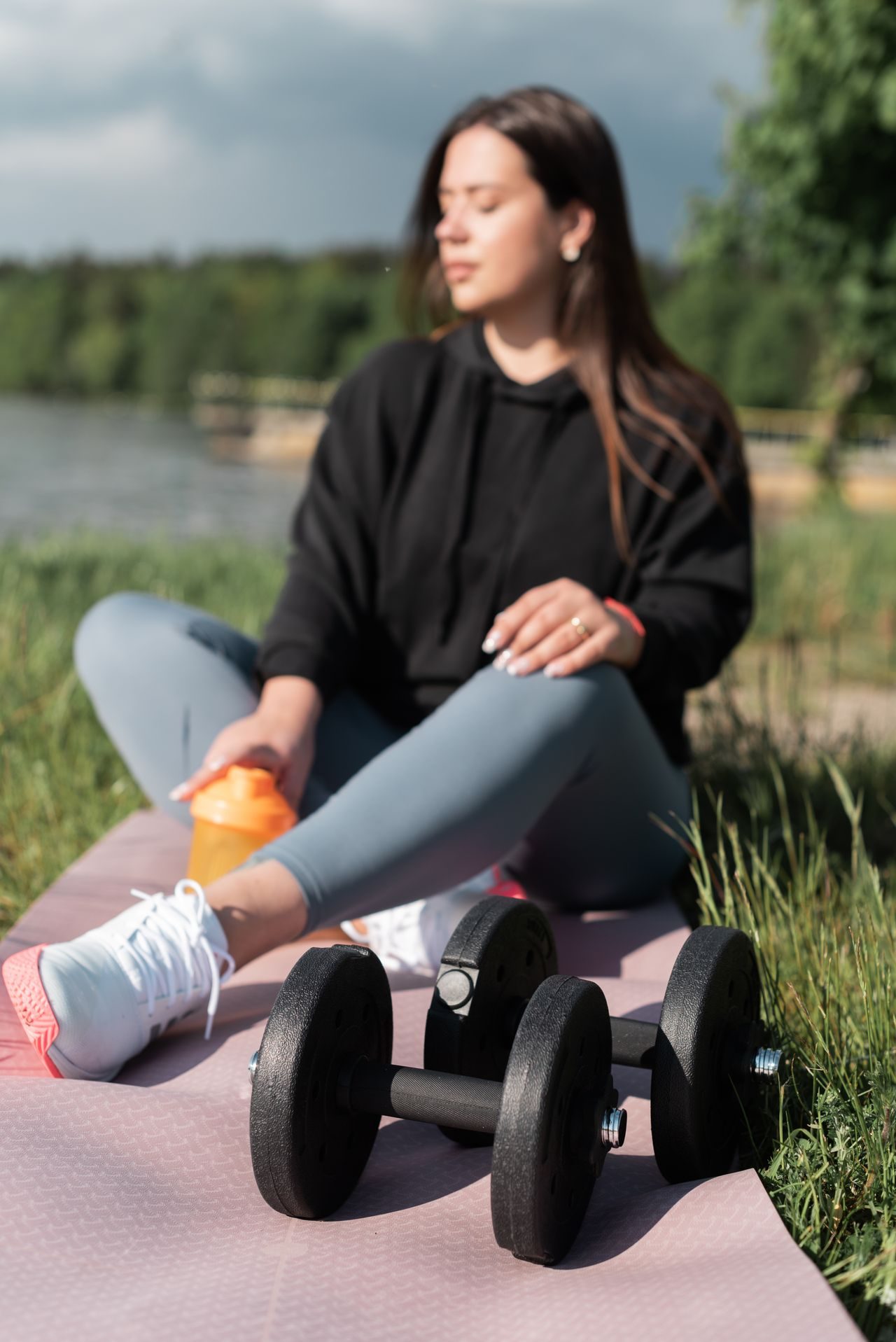 A person resting beside exercise equipment with a water bottle