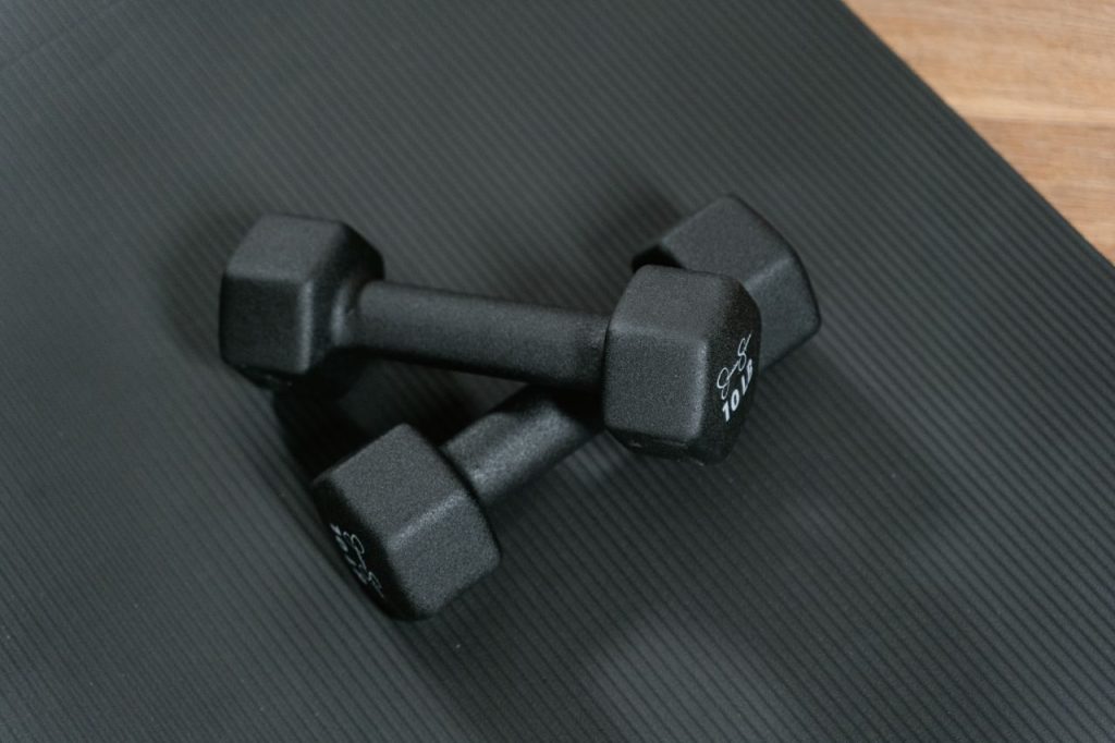 Two dumbbells on a dark exercise mat