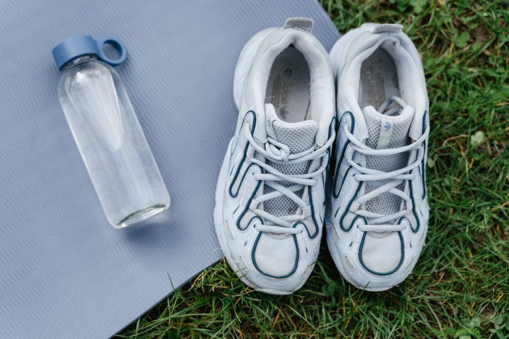 Sports shoes and a water bottle arranged on an exercise mat