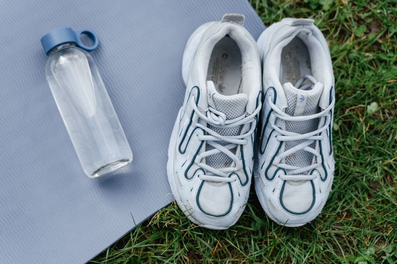 Sports shoes and a water bottle arranged on an exercise mat